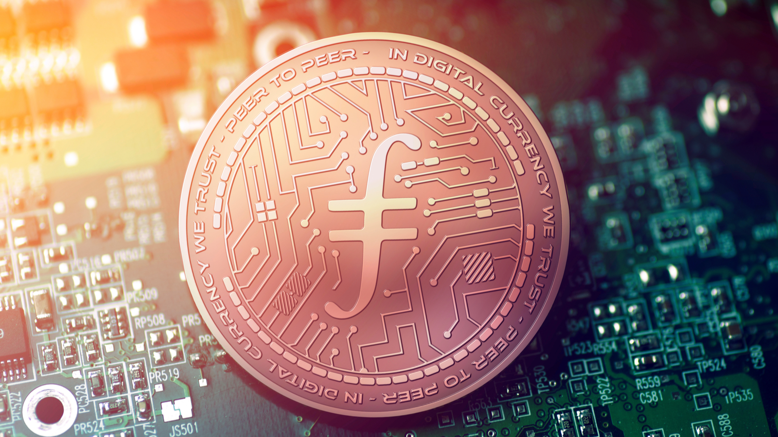 Filecoin (FIL) logo on a copper-colored coin that sits on top of a circuit board