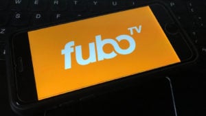 A picture of a FuboTV logo on a smart phone against a computer keyboard.