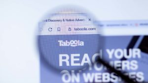 A magnifying glass zooms in on the website for Taboola.