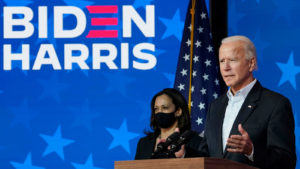 Joe Biden and Kamala Harris stand together at a podium with a campaign logo in the background.