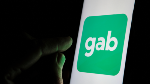 Image of a finger about to tap the Gab social media logo on a smartphone.