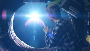 Person looking through space capsule's cabin window into space representing space stocks.