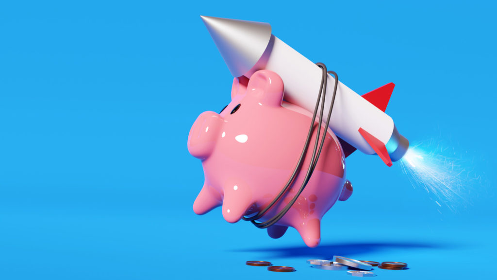 A pink piggy bank strapped to a rocket launching it into the air.