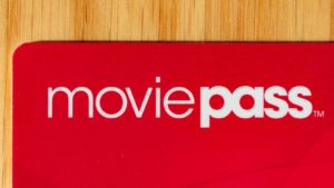 The corner of a red MoviePass (HMNY) card on a wooden surface.