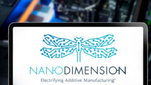 iPad の Nano Dimension (NNDM ストック) ロゴ、背景に独自の 3D プリンター