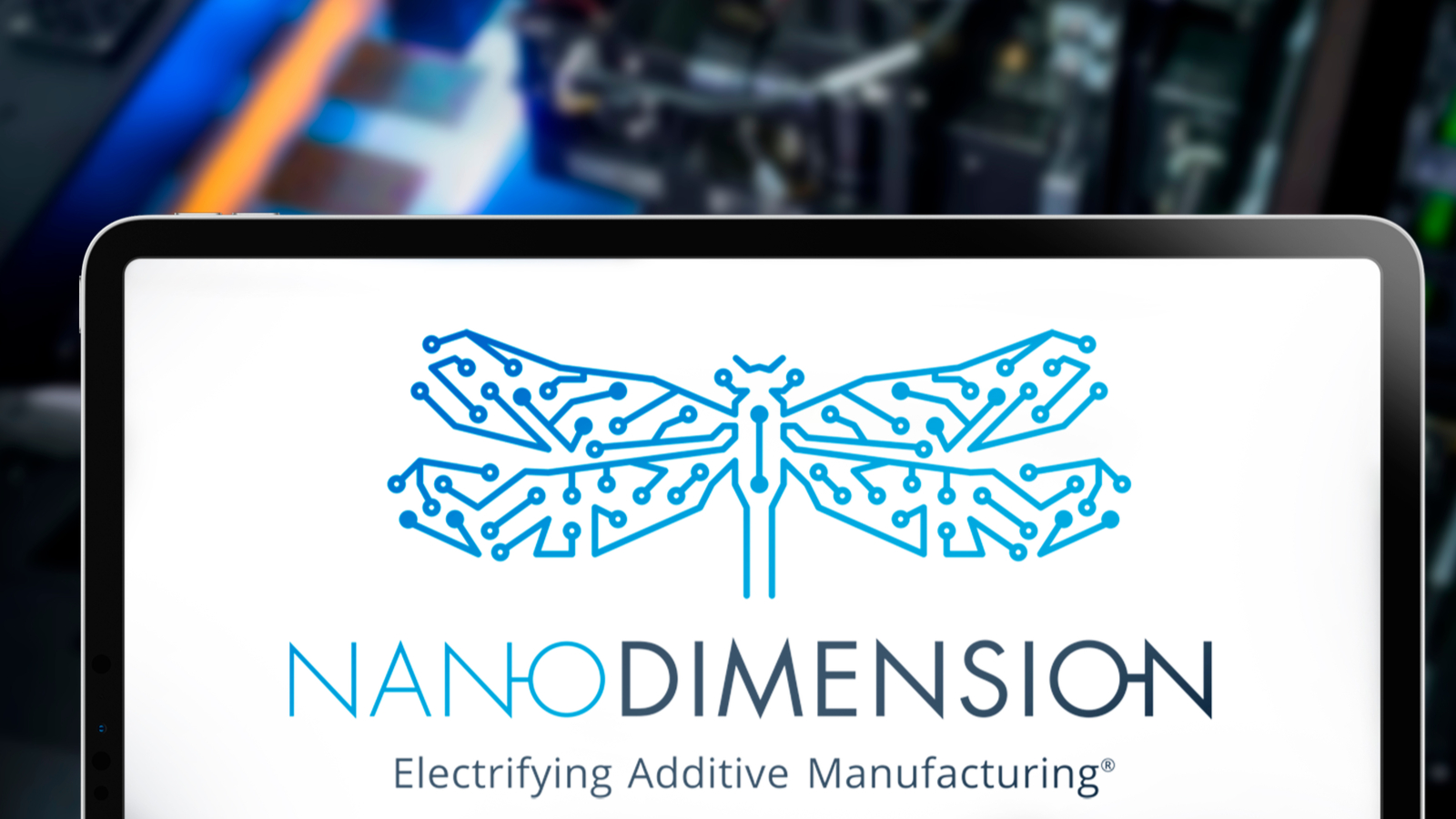 Nano Dimension (NNDM stock) logo in an iPad, on the background their proprietary 3D printer
