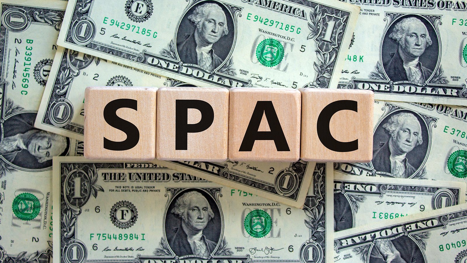 GSRM stock: An image of wooden blocks that say SPAC over a series of one dollar bills.
