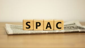 A photo of wooden blocks that say SPAC on a folded newspaper representing PetSmart SPAC Merger.