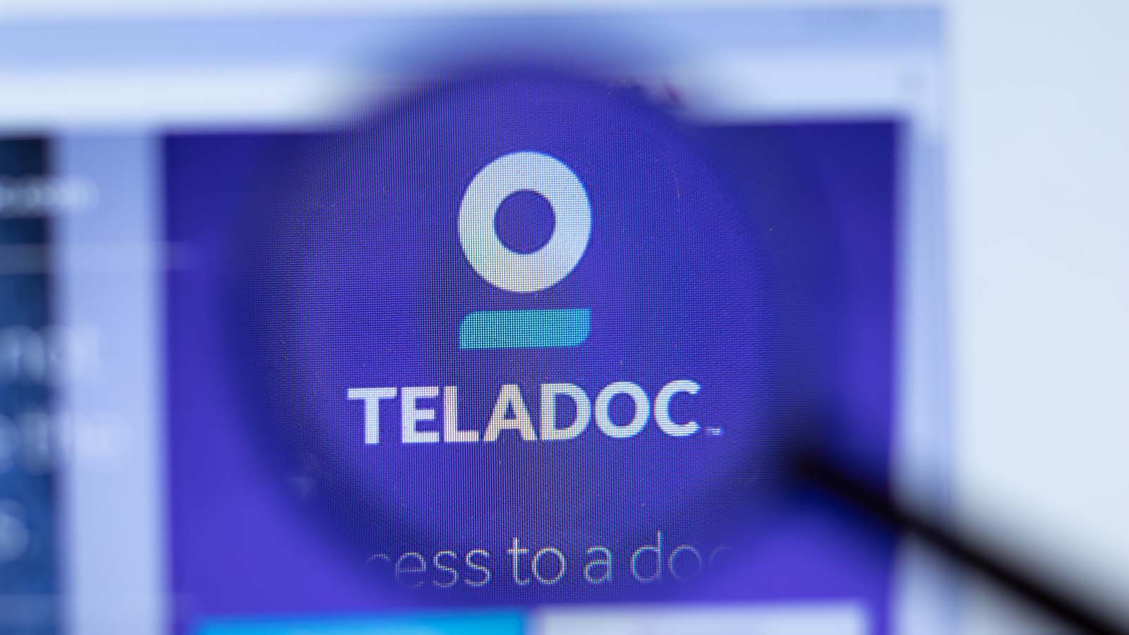 The Teladoc logo through a magnifying glass. TDOC Stock.