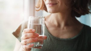 A photo of a woman holding a glass of water.