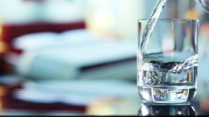 Water stocks: A photo of water being poured into a glass that's sitting on a table.