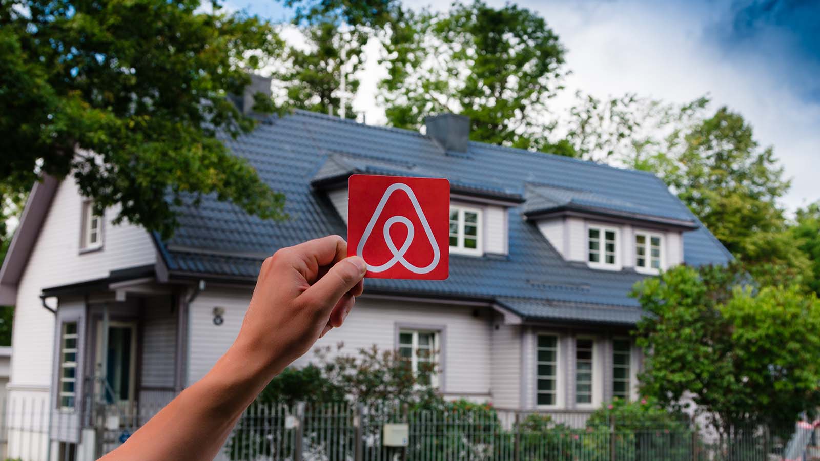 A hand holds up the Airbnb (ABNB) logo outside a home in Estonia.
