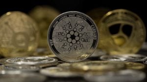 El token de Cardano (ADA) con otros tokens de oro y plata en el fondo.