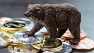 A concept image with a bear figuring standing on top of crypto tokens representing why is bitcoin down today.