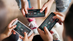 Three friends playing a mobile game against each other.