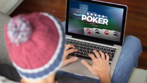 man playing poker online with laptop on the sofa.