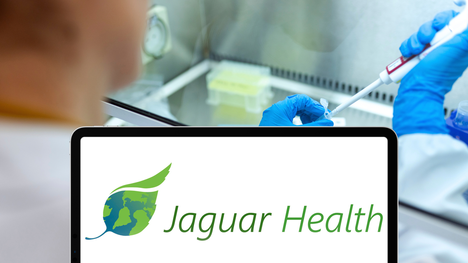 The Jaguar Health logo on a tablet in front of a doctor representing JAGX Stock.