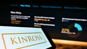 Web ページの前の画面に表示された、カナダの鉱山会社 Kinross Gold Corp. のビジネス ロゴが表示された携帯電話。