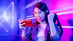 A mobile gamer cheering on her smartphone with neon background.