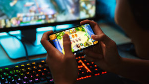 A person playing mobile games and PC games at the same time representing Splinterlands Crypto.