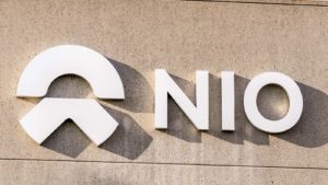 A Nio (NIO Stock) sign and logo on a tan concrete building.