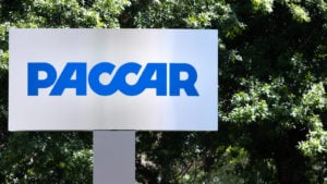 A sign for Paccar (PCAR) in front of greenery.