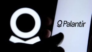 A close-up shot of a hand on a screen with the Palantir (PLTR stock) logo.