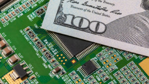 A $100 bill resting on top of a computer motherboard, a technology produced with rare earth metals