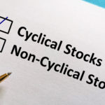 The phrases 'Cyclical Stocks' and 'Non-Cyclical Stocks' are printed on a piece of paper with boxes next to them. A check mark has been drawn in the Cyclical Stocks box, and a pen rests on the paper.