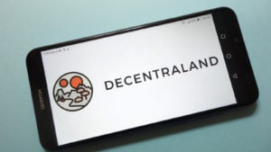 Decentraland logo displayed on smartphone screen, teal background behind the phone representing Decentraland Price Predictions.