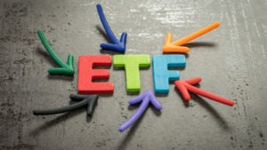 Colorful arrows pointing at the multicolored word "ETF" against a cement surface