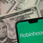 Robinhood app logo seen on smartphone on US dollar banknotes