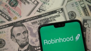 Robinhood app logo seen on smartphone on US dollar banknotes representing the HOOD stock IPO.