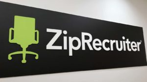 A banner for ZipRecruiter (ZIP) stretches across a blank white wall.