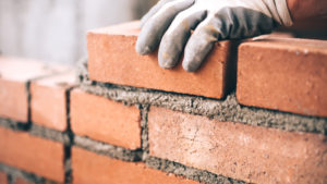 Close up of industrial mason installing bricks at construction site