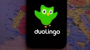 The Duolingo (DUOL) logo on a smartphone screen with a map in the background.