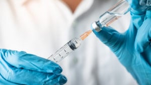 OCGN stock: hands of medical professional holding a syringe, symbolizing vaccine representing Free At-Home Covid Test.