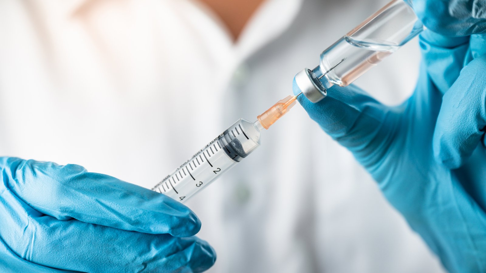 Hands of medical professional holding a syringe, symbolizing PCVX stock.