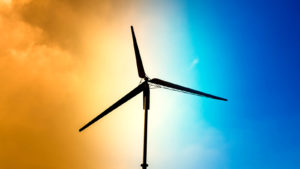 A wind turbine appears against a bright orange and blue sky.