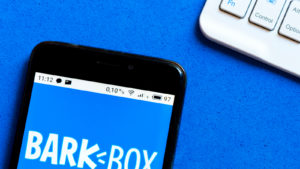 a BarkBox (BARK) logo is seen displayed on a smartphone.