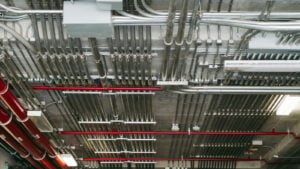 An array of electrical conduits are lined up in a row across the ceiling of a room.