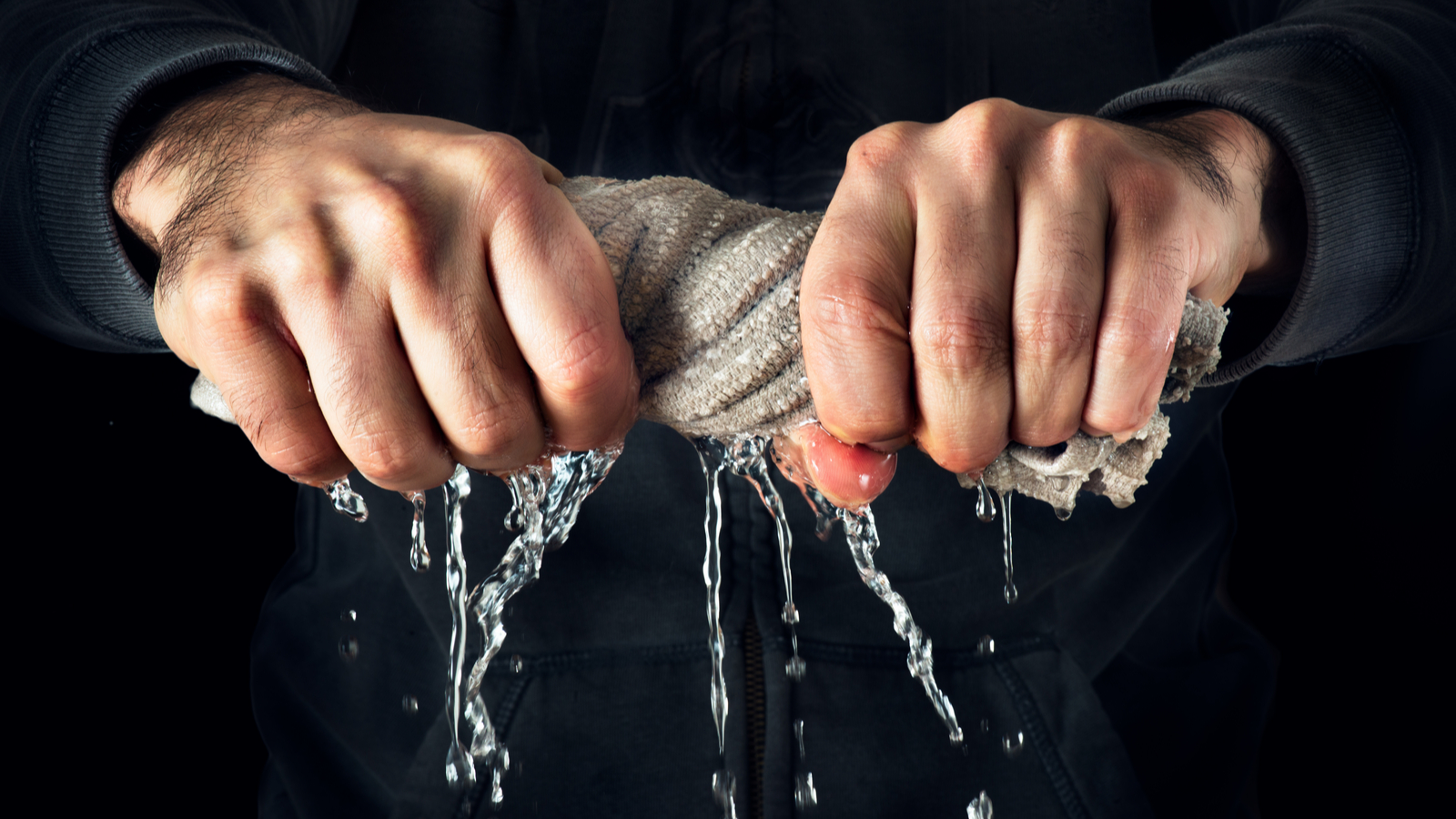 Man squeezing water out of a rag representing short squeeze stocks and QNRX stock.