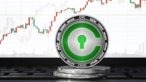 cryptos: a Civic (CVC) concept coin sitting upright on a computer keyboard with a chart on the screen in the background