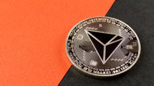 cryptos: a TRON (TRX) concept coin against an orange and black background