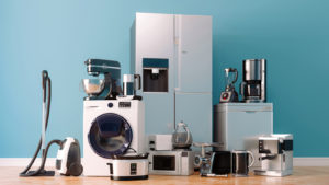 a group of appliances in front of a blue wall, including a washing machine, a refrigerator, a microwave and more