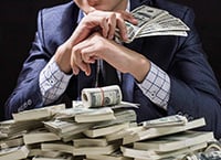 man sitting behind a pile of money