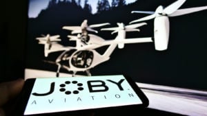 Person holding smartphone with logo of startup and aerospace company Joby Aviation (air taxi) on screen representing JOBY Stock.