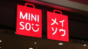 red Miniso (MNSO) sign glowing at night. Chinese stocks to buy