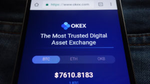 The website for OKEx is shown on a smartphone.