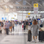 two women carrying luggage in an airport